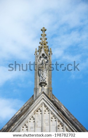 Winchester, UK - June 13, 2014: Stone carving of St. Swithun atop the west facade of Winchester Cathedral, England. The Anglo-Saxon bishop is patron saint of the cathedral.