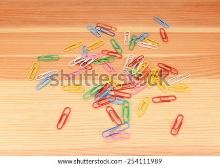 Multi-coloured paper clips scattered across a wooden background