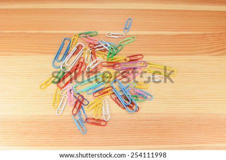 Large and small coloured paper clips on a wooden background