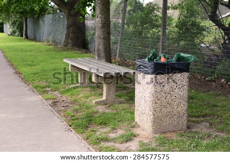 A full rubbish bin makes an empty bench an unwelcoming place to rest