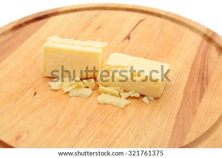 Small blocks of crumbly cheddar cheese on a wooden board