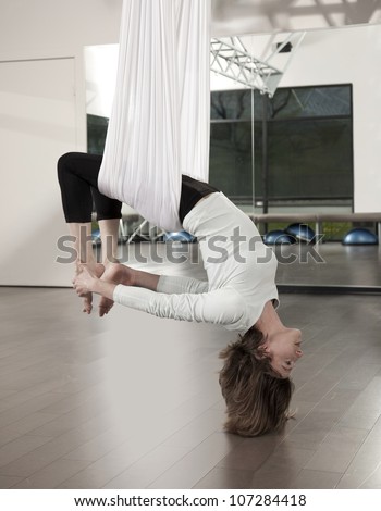 Woman doing anti gravity yoga exercise in fitness center.