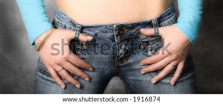 girl\'s thumbs hooked in jeans belt loops