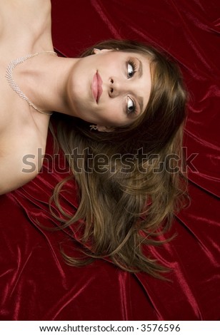 head and shoulders shot of brunette girl on red fabric. shot from above.