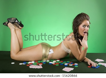 Young brunette woman lying on card table wearing sexy lingerie. Mischievous expression.