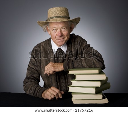 Front view of mature man seated at table with stack of textbooks. Studio photo.
