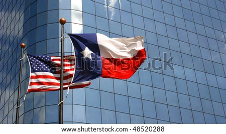 American and Texas flags in front of a skyscraper