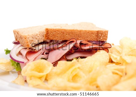 Delicious ham sandwich platter with whole wheat bread and potato chips