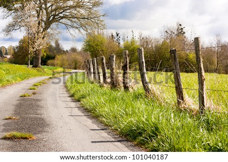 Countryside landscape in France with a small road and fence pasture