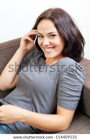 Pretty brunette lying on a sofa and phoning