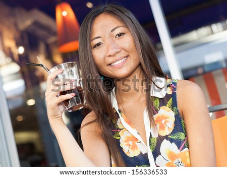 Close up portrait of a beautiful asian girl drinking a soda sitting on terrace