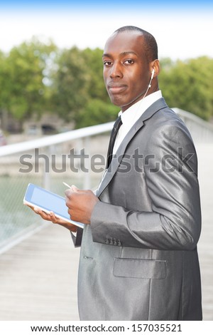 Portrait of a busy businessman using mobil phone with hands-free headset and using electronic tablet