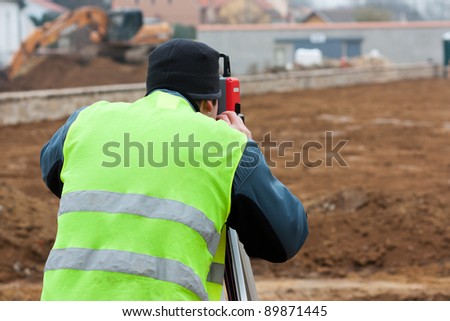 Building surveyor taking measurements on a construction site
