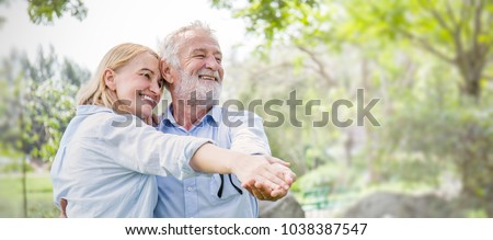 Happy old couple smiling dancing in a park on a sunny day, hoot senior couple relax in the forest spring summer time. Healthcare lifestyle retirement concept banner