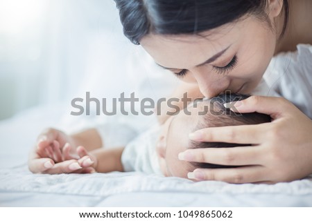 Close up portrait of beautiful young asian mother kissing her newborn baby. Healthcare and medical love lifestyle mother\'??s day concept