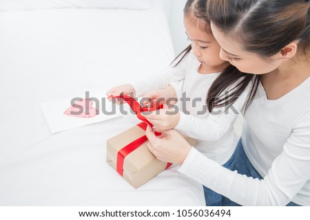 Asian little girl help her mother open gift box, celebration holiday christmas mother'??s day concept.