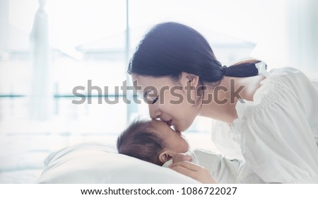 Close up portrait of beautiful young asian mother kissing her newborn baby. Healthcare and medical love lifestyle mother\'s day concept banner