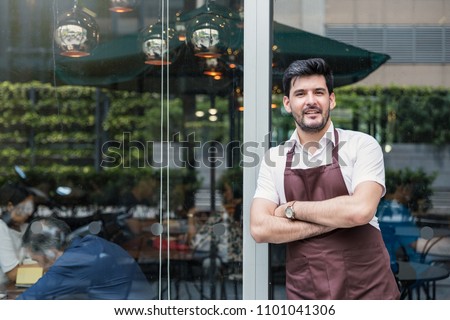 Startup successful small business owner man walking in his coffee shop or restaurant. Portrait of young caucasian man successful barista cafe owner