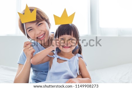 Portrait of mother and child daughter playing having fun together. Beautiful funny girl and mommy have crowns on sticks. Fun love family lifestyle single mom love mother’s day holiday concept