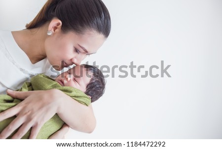 Closeup portrait of beautiful young asian mother kissing her newborn baby sleeping on hospital bed. Healthcare and medical family love lifestyle breastfeeding nursery mother’s day concept