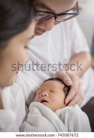 Asian parents with newborn baby, Close up portrait of asian young couple holding their new born baby. asian father with his hands holding baby head.