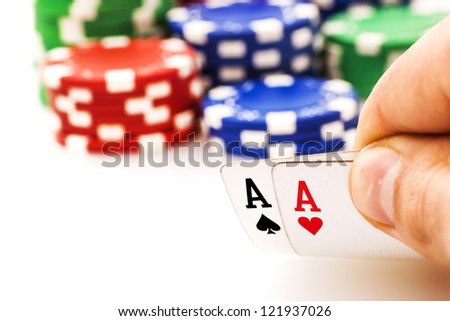 Pair of aces in hand and poker chips isolated on black background