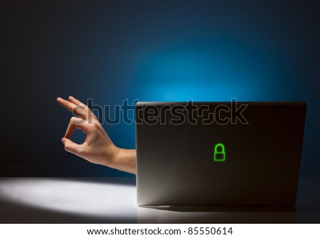 A hand is reaching out from a laptop giving the OK hand signal.