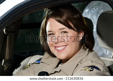 a female police officer smiles while sitting in her patrol car.