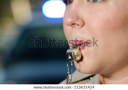 a female police officer about to blow into her whistle as she directs traffic.