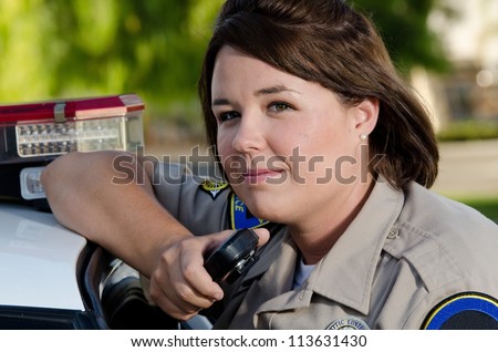 a female police officer holds the radio as she\'s about to talk into it.