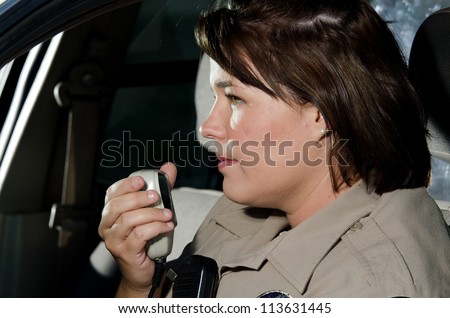 a profile of a police officer sitting in her car as she\'s about to talk on the radio.