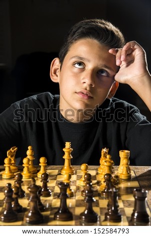An 11 year old boy thinking about his next move during a chess game.