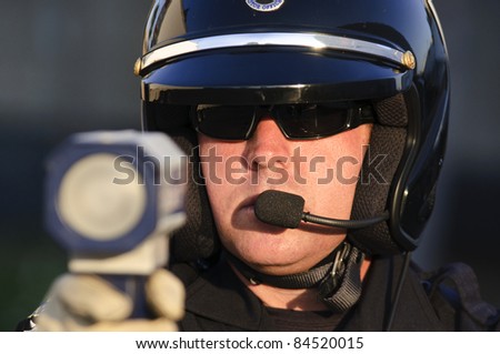 a police officer pointing his radar gun at speeding traffic.