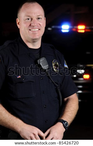 a smiling police officer in front of his patrol unit.