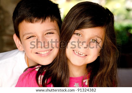 a happy brother and sister smiling for their portrait