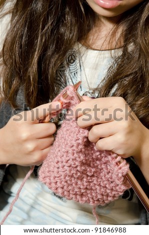 a 7 year old little girl sits on the couch as she learns to knit.