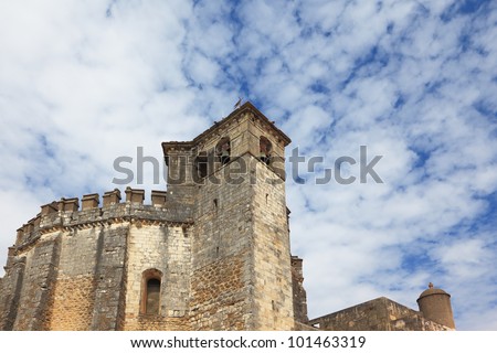 The imposing medieval castle - the monastery of the Templars. Powerful round tower and bell tower on the background of the cloudy sky