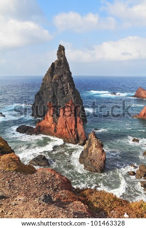 Bright red and gray cliffs east of the island. Windy day on the ocean island of Madeira.