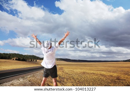 Road to the Grand Canyon. The tourist in a white easy shirt admires beauty of a landscape. Autumn yellow fields and the magnificent cloudy sky