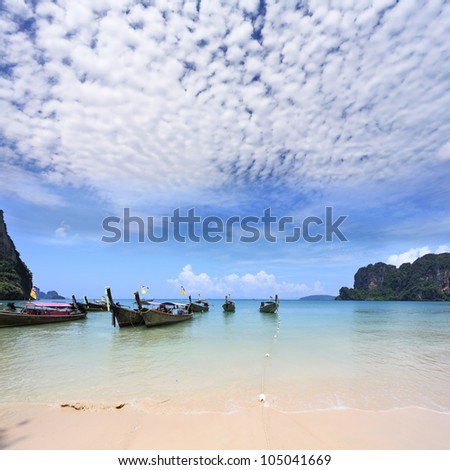 Light cirrus clouds over the warm sea. Picturesque native boat Longtail waiting on the beach the first tourists