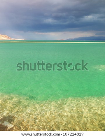 Sunset. Incredible lighting effects in a thunderstorm at the Dead Sea. Multi-colored water in the shallows