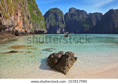 Emerald water lapping at the cliffs. A secluded cove off the coast of Thailand