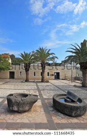 Courtyard of the ancient church on the Sea of Galilee. Ancient rocks to get olive oil, and palm trees