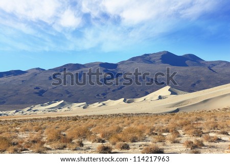 Cold morning in the desert. The famous Eureka - a giant sand dune in California. Background - dark black mountains
