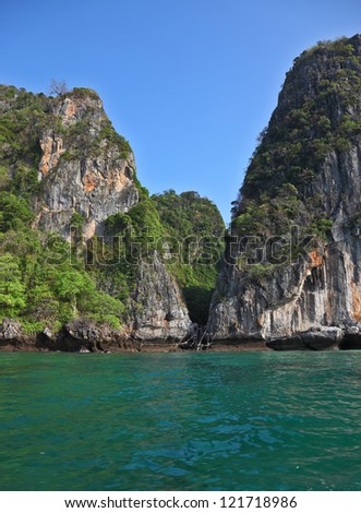 A secluded cove off the coast of Thailand. Emerald water lapping at the cliffs
