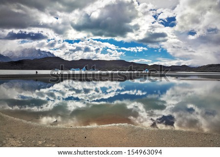 The mysterious glow. Bright reflections of sky and clouds in the smooth cold water of Lake Grey. Chilean Patagonia, National Park Torres del Paine