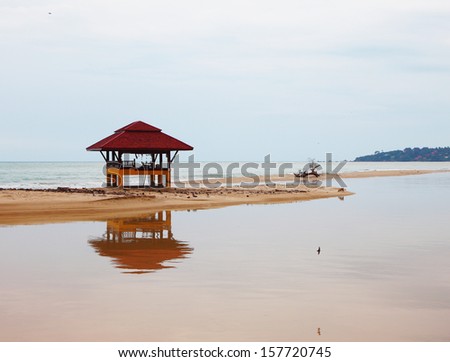 Sandy beach on Koh Samui. The red beach wooden arbor is picturesquely reflected in water