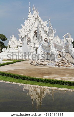 White fabulous palace in Southeast Asia. The elegant facade is reflected in a pond with live fish