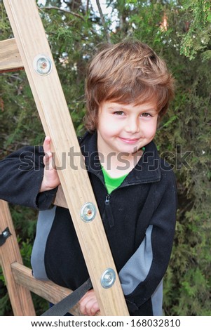 Very beautiful blond boy climbed a wooden extension ladders in the garden