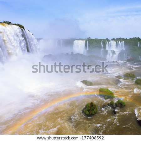 White whipped foam of water and a thin mist over the water. Magnificent rainbow bent in mist. The most high-water waterfall in the world - Iguazu. The picture is taken by lens Fisheye